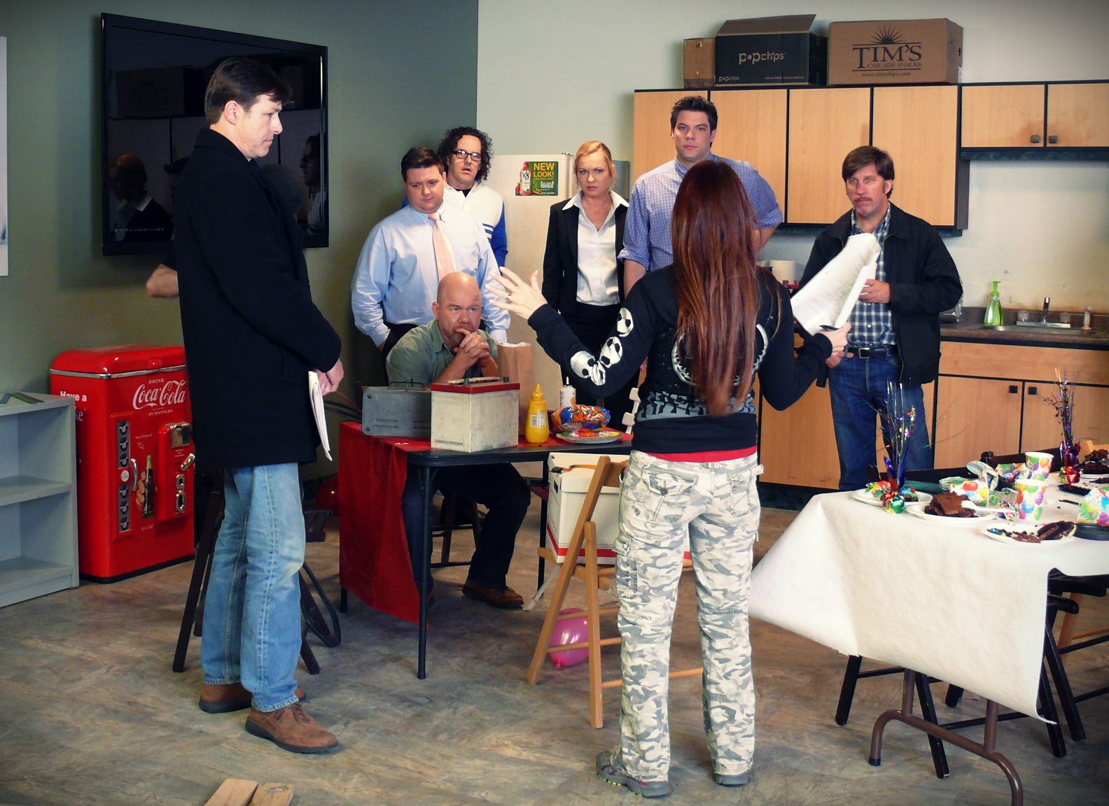 Annie Biggs, seen from behind, directing a group of actors in rehearsal