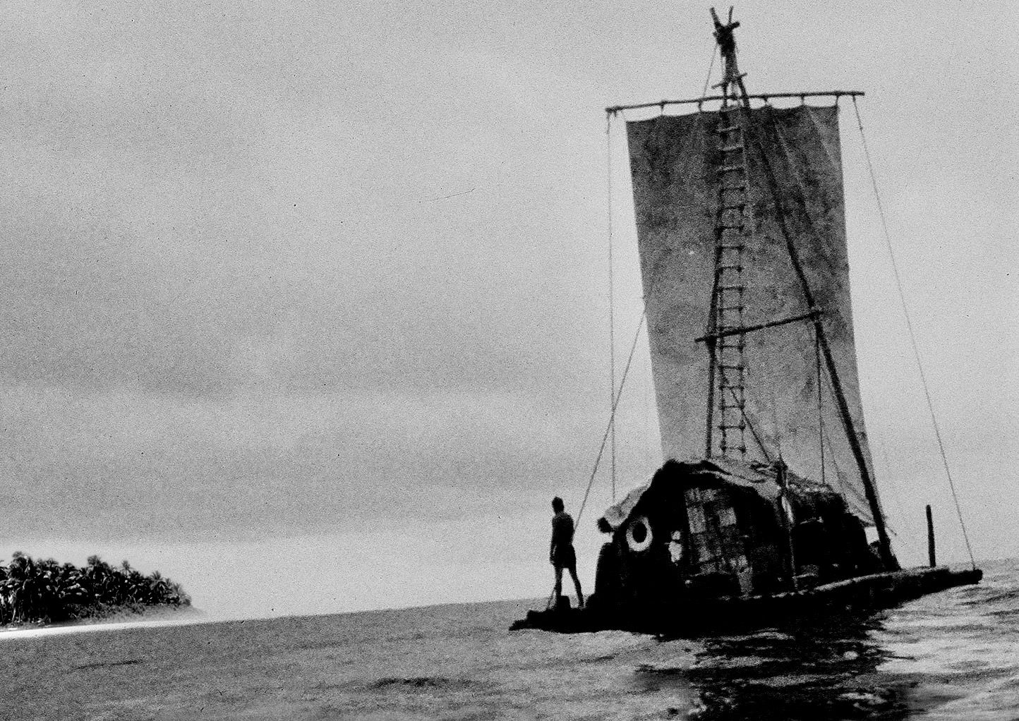 An ancient-style balsa sail raft at sea, with a low island on the horizon